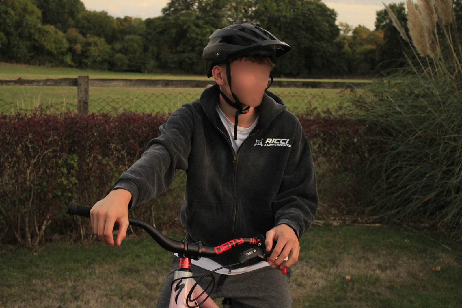 Helmeted rider wearing the black Ricci Components Sun Fade Zip-Up Hoodie